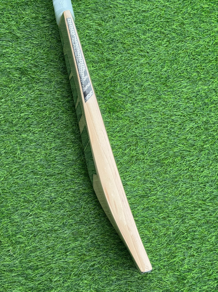 Side profile view of MB Malik UMZ GOAT Cricket Bat showing thick edges on green turf - Albert Cricket Store